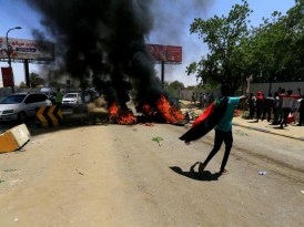 A Sudanese protesters gestures as they burn tyres and barricade the road leading to al-Mek Nimir Bridge crossing over Blue Nile; that links Khartoum North and Khartoum